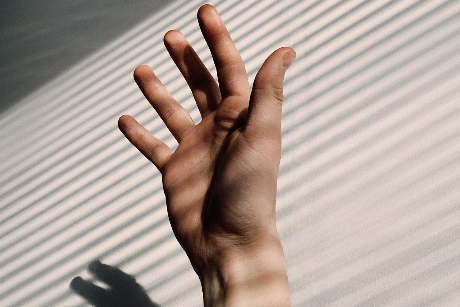 hand in sunlight with shadows of horizontal lines going across it